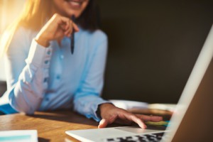 Closeup woman using laptop holding pen, half body visible